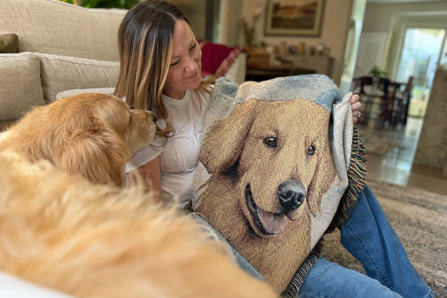 A dog owner holding a woven portrait blanket beside her golden retriever